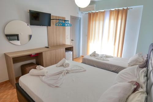 a room with two beds and a tv and a mirror at Hotel Driloni in Ksamil