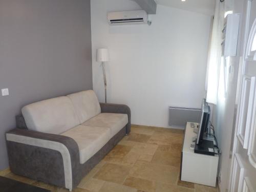 a living room with a couch and a tv at Le Gîte du Moulin in Sarrians