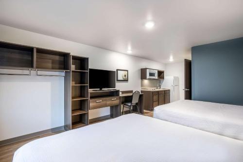 ein Hotelzimmer mit 2 Betten und einem Schreibtisch mit einem TV in der Unterkunft WoodSpring Suites Gurnee - Chicago in Gurnee