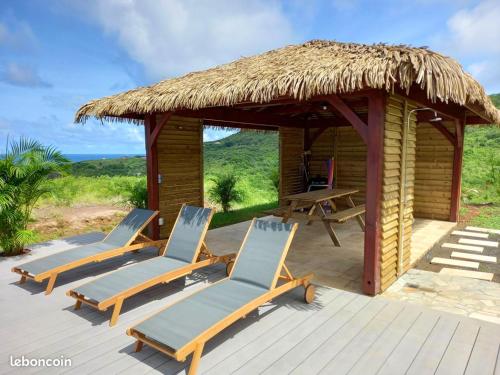 a deck with two chairs and a hut at Villa de 4 chambres avec vue sur la mer piscine privee et jacuzzi a Le Marin a 3 km de la plage in Le Marin