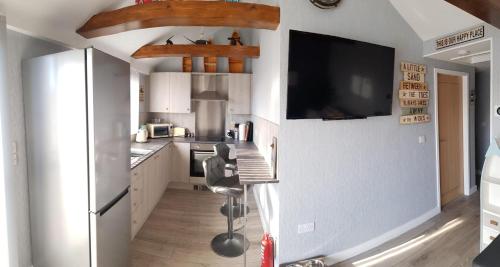a kitchen with a refrigerator and a tv on the wall at luxury 2-Bed modern chalet in Bridlington in Bridlington