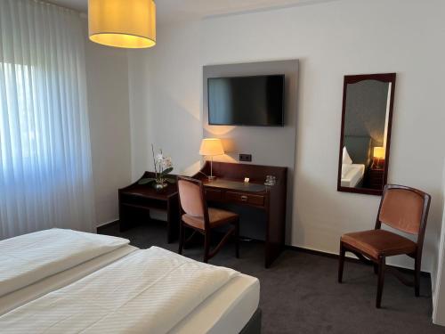 a hotel room with a bed and a desk and a mirror at Hotel Garni Geisler in Cologne