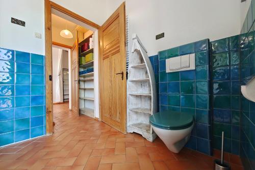 a bathroom with a toilet and blue tiled walls at FeWo Loft Vorwerk Seehausen - Uckermark - mit großer Terrasse in Seehausen