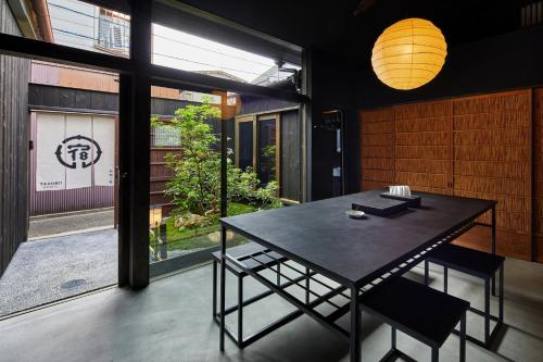 een eetkamer met een tafel en een groot raam bij YADORU KYOTO HANARE Washi No Yado in Kyoto