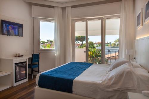 a bedroom with a bed and a fireplace and windows at Hotel Tarabella in Forte dei Marmi