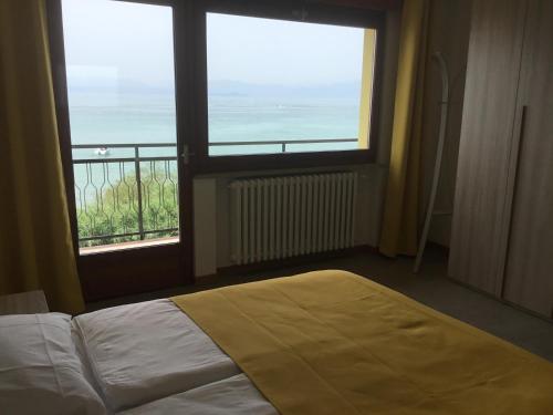 a bedroom with a bed and two windows with a view at CASA COSTA AL SOLE APARTMENT 2 in Lazise