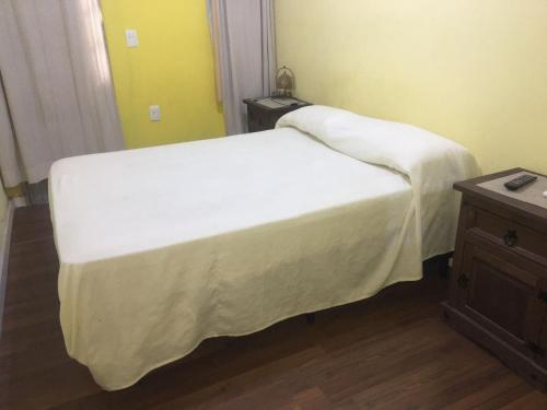 a bedroom with a bed with white sheets and a table at Relax V in Paysandú