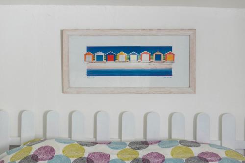 ein Gemälde von Strandhütten an einer Wand über einem Bett in der Unterkunft Appartement Royan Rayley in Royan