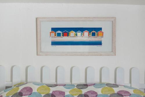 a painting of beach huts on a wall above a bed at Appartement Royan Rayley in Royan