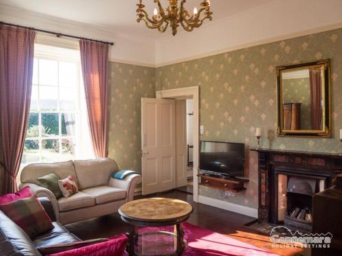 a living room with a couch and a tv at Kill House, Kingstown in Clifden