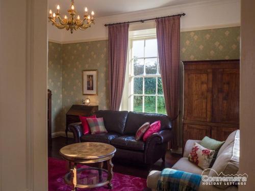 a living room with a leather couch and a window at Kill House, Kingstown in Clifden