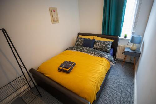 um quarto com uma cama com um cobertor amarelo e almofadas em Sterling Aparment em Wallsend