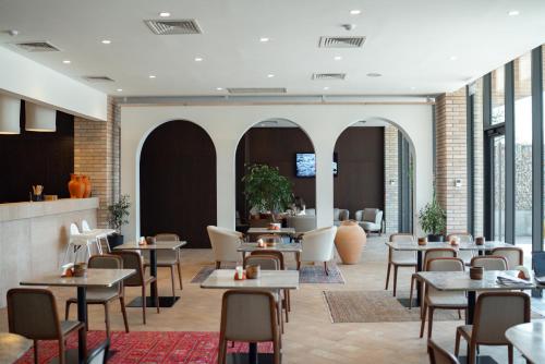 a restaurant with tables and chairs and windows at Pana Boutique Hotel in Shymkent