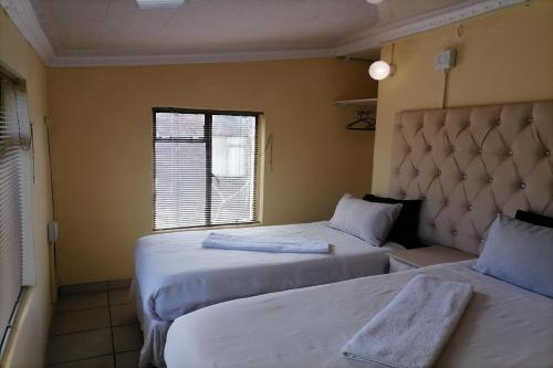 a hotel room with two beds and a window at Maluti Backpackers in Phuthaditjhaba