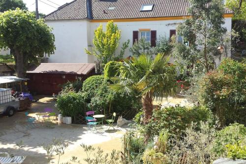 un giardino di fronte a una casa con una palma di GITE douillet CHAUVRY 24Km PARIS a Chauvry
