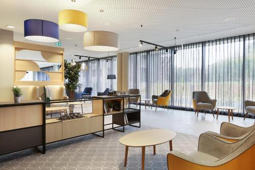 布拉尼亚克Appart Hotel Odalys City Toulouse Blagnac Aéroport的一个带桌椅和大窗户的办公大厅