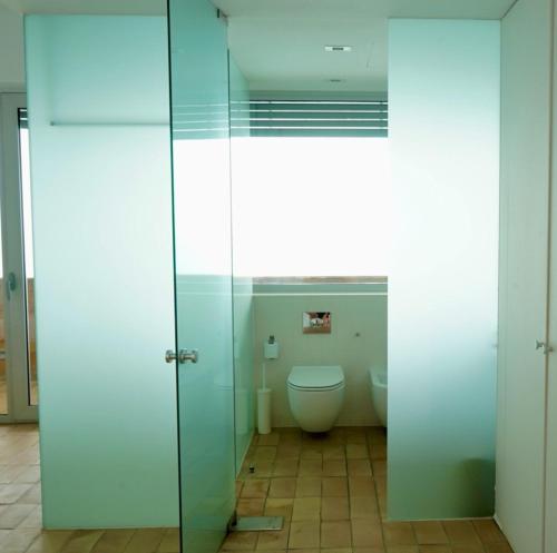 a bathroom with a toilet and a glass door at Iris Zahara in Zahara de los Atunes