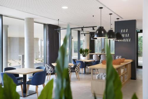 une salle à manger avec tables, chaises et fenêtres dans l'établissement Appart Hotel Odalys City Toulouse Blagnac Aéroport, à Blagnac
