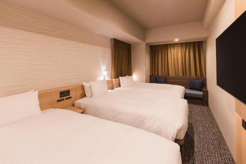 東京にある相鉄グランドフレッサ 高田馬場のベッド3台と窓が備わるホテルルームです。