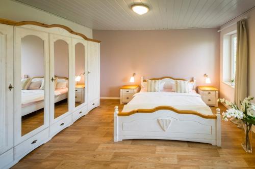 a bedroom with a white bed and a mirror at "Ferienhof Seelust" Ferienwohnung Rose in Gammendorf