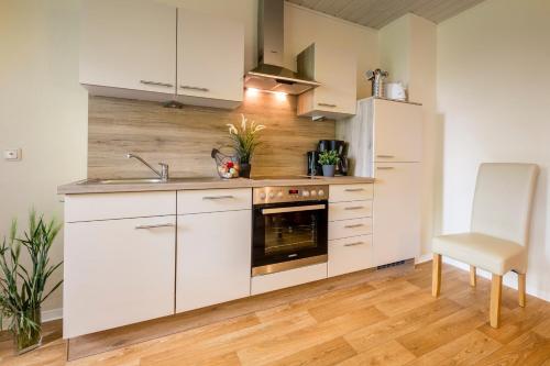 a kitchen with white cabinets and a sink and a stove at "Ferienhof Seelust" Ferienwohnung Rose in Gammendorf