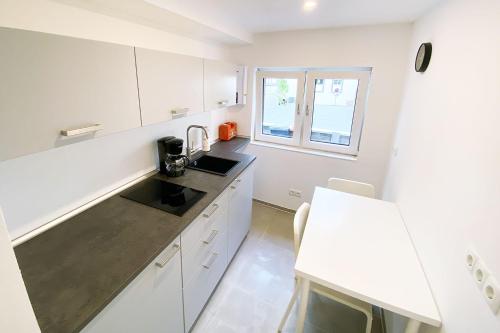 a kitchen with white cabinets and a sink and a window at 2 room house for workers in Linz am Rhein