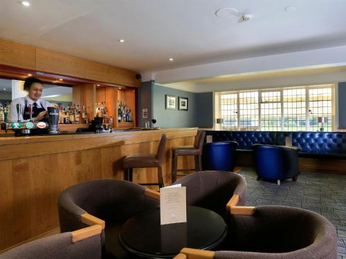 a woman standing at a bar in a restaurant at Macdonald Craxton Wood Hotel & Spa in Ledsham