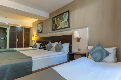 a hotel room with two beds and a mirror at Lazz By Ketenci Hotel in Izmir