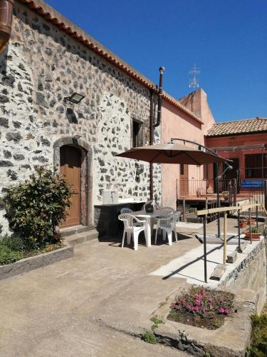 a patio with a table and an umbrella in front of a building at Villa Etna Masi' in Milo