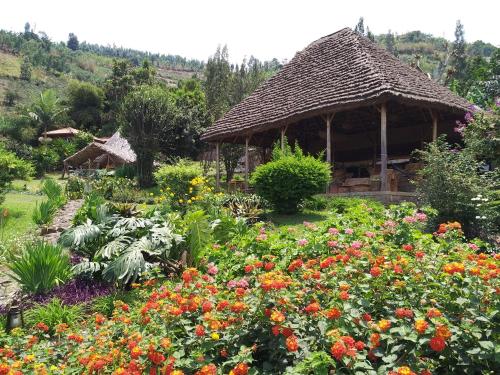 a garden with flowers in front of a gazebo at INZU Lodge in Gisenyi