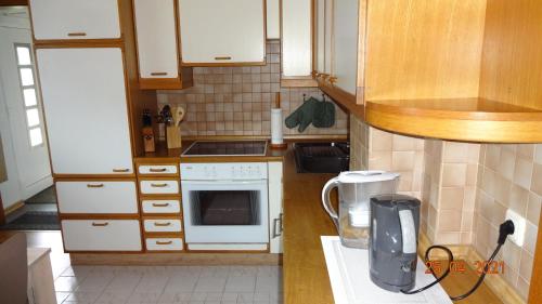 a small kitchen with white appliances and wooden cabinets at FeWo Eberau in Ebrach