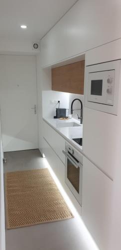 une cuisine blanche avec un évier et un micro-ondes dans l'établissement Destinu Marinella, à Ajaccio