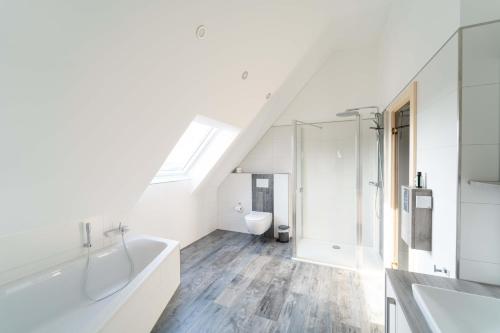 ein Badezimmer mit Waschbecken, Badewanne und Toilette in der Unterkunft Ferienhaus Seeblick am Harkebrügger See mit Sauna und Kamin in Barßel