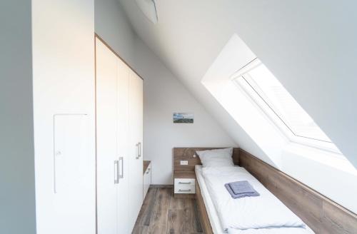 a attic bedroom with a bed and a window at Ferienhaus Seeblick am Harkebrügger See mit Sauna und Kamin in Barßel
