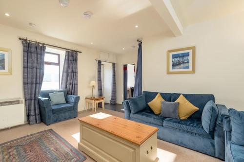 a living room with a blue couch and two chairs at Melfort Village in Oban