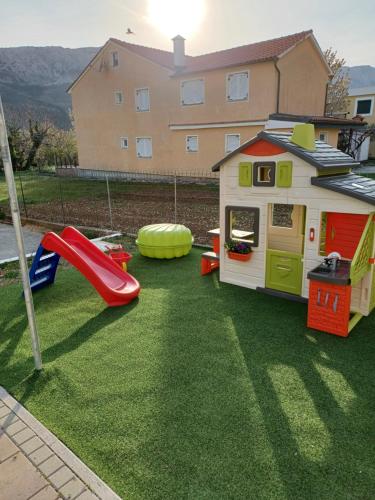 een speelhuis met een glijbaan en een speeltuin bij Apartments Polonijo in Baška