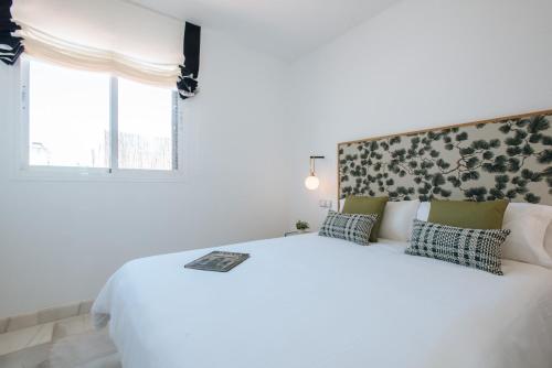 a white bedroom with a large white bed and a window at Magno Apartments Redes Terrace in Seville