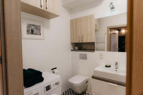 a white bathroom with a sink and a toilet at Flathouse Apartment Centrum in Białystok