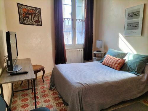 een slaapkamer met een bed, een bureau en een televisie bij Etablissement Roussel in Saint-André-de-Sangonis