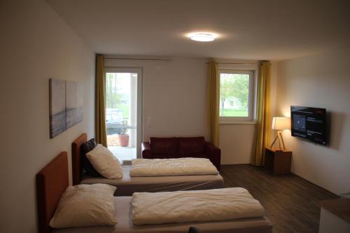 EngerwitzdorfにあるAparthotel Kreuzwirtのベッド2台とソファが備わるホテルルームです。