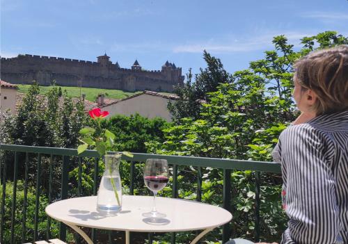 una donna seduta a un tavolo con un bicchiere di vino di La Villa Carcassonne, Cité 8 min à pieds, Clim, Piscine, Full Wifi, Borne 7,5kW, Vélo élect, Parking privé a Carcassonne