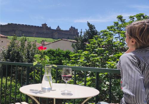 a woman sitting at a table with a glass of wine at La Villa Carcassonne, Chambres d hôtes, B&B, face à la Cité Médiévale in Carcassonne