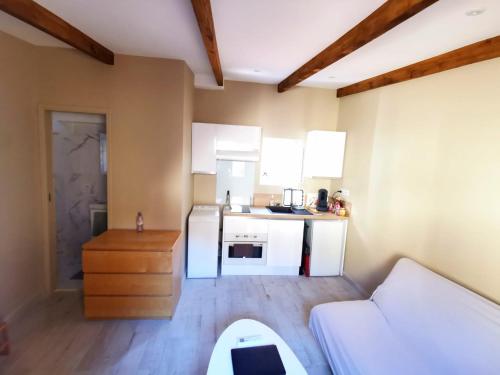 a small kitchen with white cabinets and a white couch at Studio lumineux à 10 min de la plage in Nice