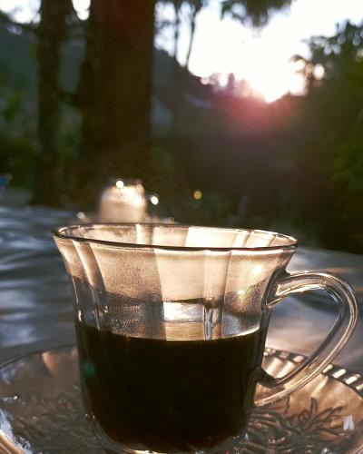 a glass cup of coffee sitting on a table at Casa Dos Artistas in Penedo