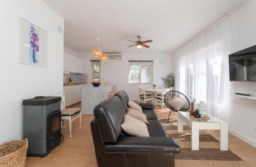 sala de estar con sofá de cuero negro y cocina en Vacation house Benedetto, en Supetar