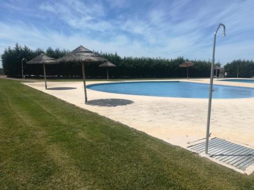 a swimming pool with umbrellas next to a field at Casa dos Sobreiros in Cuba