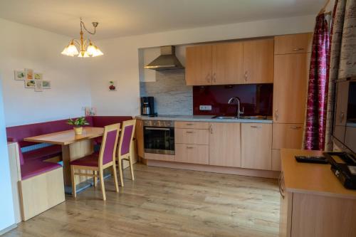 a kitchen with wooden cabinets and a table with chairs at Appartement Höllwarthof in Goldegg