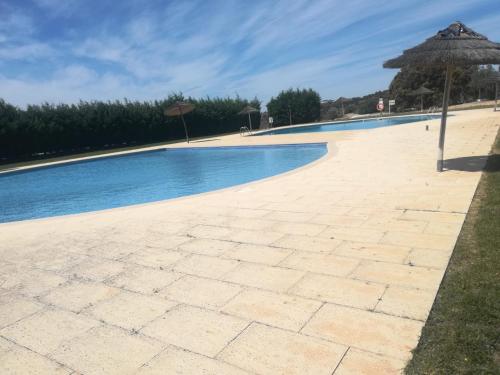 a swimming pool with an umbrella next to it at Casa dos Sobreiros in Cuba