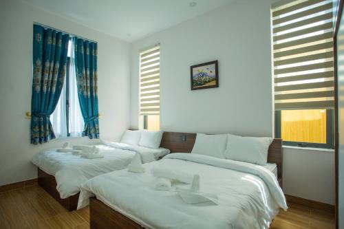 two beds in a room with blue walls and windows at Win Villa Coffee in Da Lat