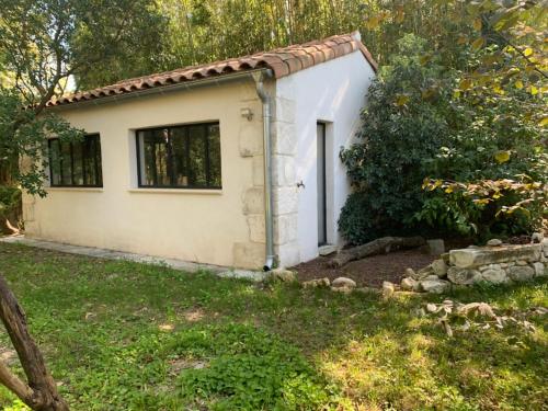 a small white house with a door in a yard at CHAMBRE D’HÔTE CHARLAMBIAS in Vallabrègues